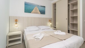 A hotel room with a wooden headboard, two beds with white linens, a large wardrobe, and a painting of a pier. - VILLA BLANCA - Beautiful villa with private swimming pool and free WIFI (Felanitx)