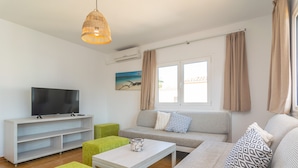 A modern living room with a flat-screen TV, a sofa, a coffee table, and a wicker pendant light. - VILLA BLANCA - Beautiful villa with private swimming pool and free WIFI (Felanitx)