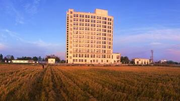 A large, multi-story building with a flat roof, surrounded by a field.