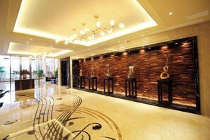 A hotel lobby with a polished floor, a modern chandelier, and a wall with trophies. - Heico Hotel (Taishan)
