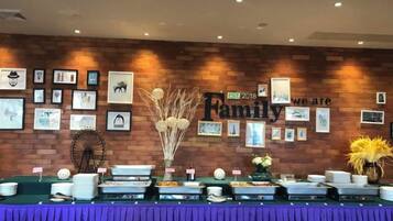A buffet setup with a brick wall and framed pictures, a sign reading 'Family 2018', and a purple tablecloth.