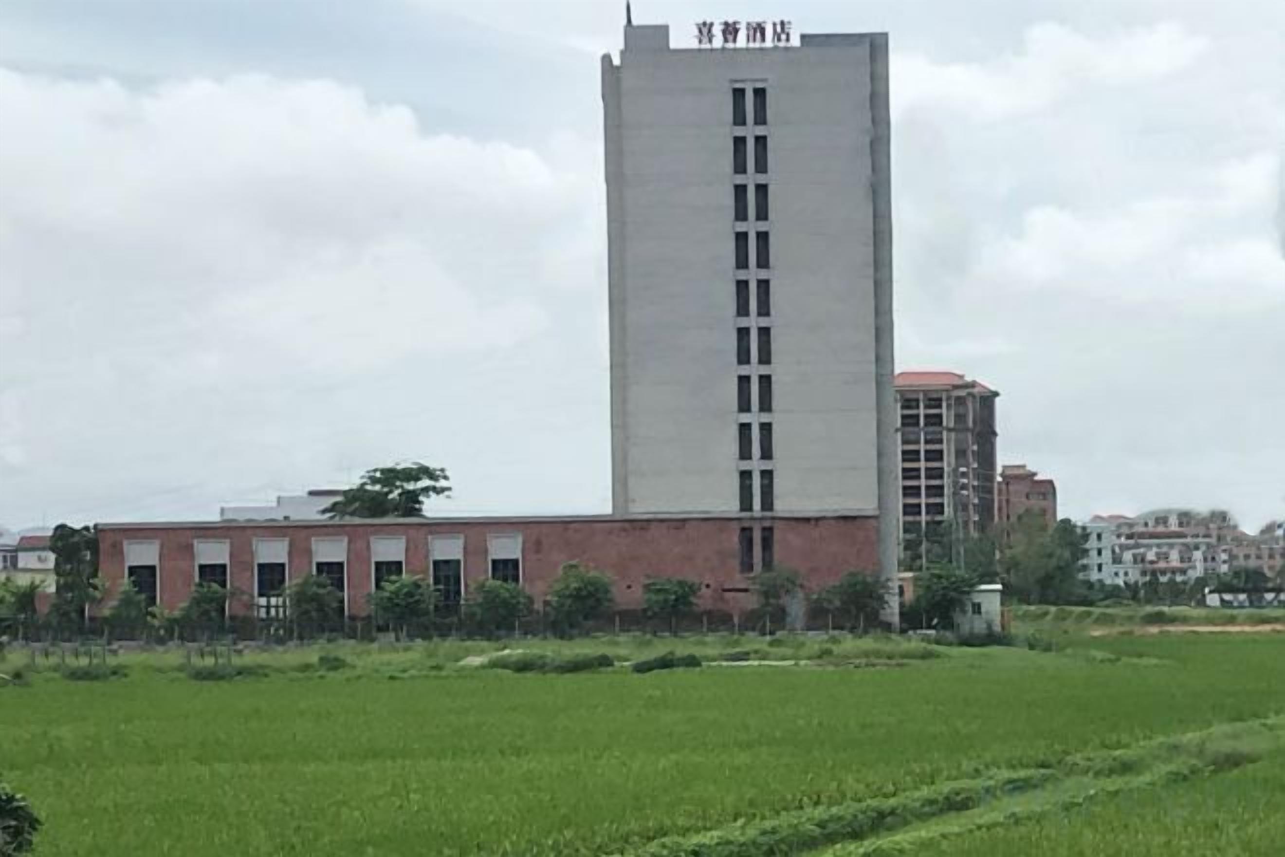 A building with a central tower and a flat-roofed structure in the background.