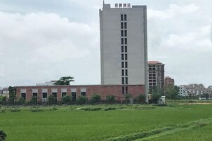 A building with a central tower and a flat-roofed structure in the background.
