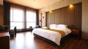 A hotel room with a large bed, a desk, and a chair.