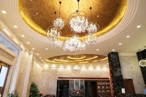 A lobby with a large chandelier, marble walls, and a reception desk. - Heico Hotel (Taishan)