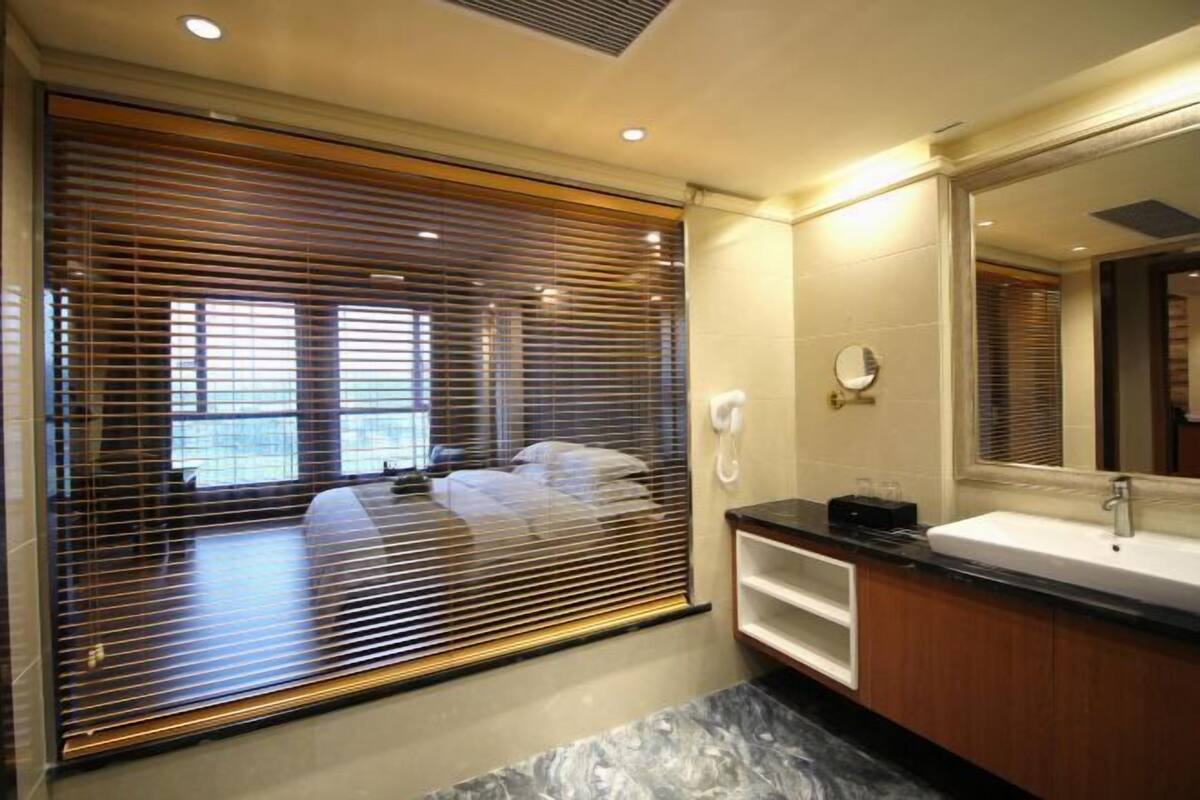 A modern bathroom with a large mirror, a sink, and a toilet.