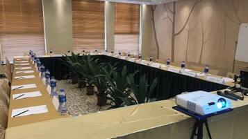 A conference room with a long table, nameplates, water bottles, and a projector.