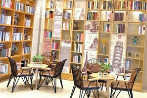 A library with bookshelves, tables, chairs, and decorative elements. - Heico Hotel (Taishan)