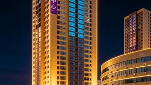 Un edificio de gran altura con varios pisos, ventanas iluminadas y un letrero destacado.