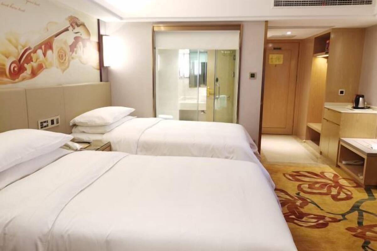 A hotel room with two beds, a shower, a desk, and a small seating area.