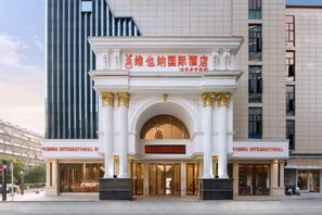 Una entrada de hotel con fachada clásica, columnas y un letrero que indica que es un hotel Vienna International.