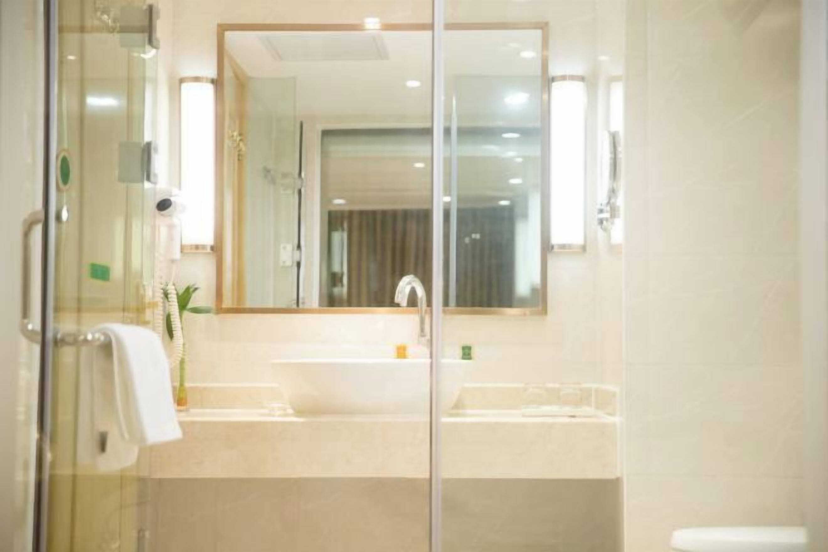 Un baño con cabina de ducha de vidrio, un lavamanos y un espejo.