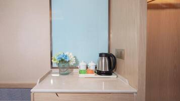 A hotel room with a white marble countertop, a vase with flowers, a tea set, and a kettle.