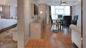 Una habitación de hotel con cama, escritorio, sillas y televisor.