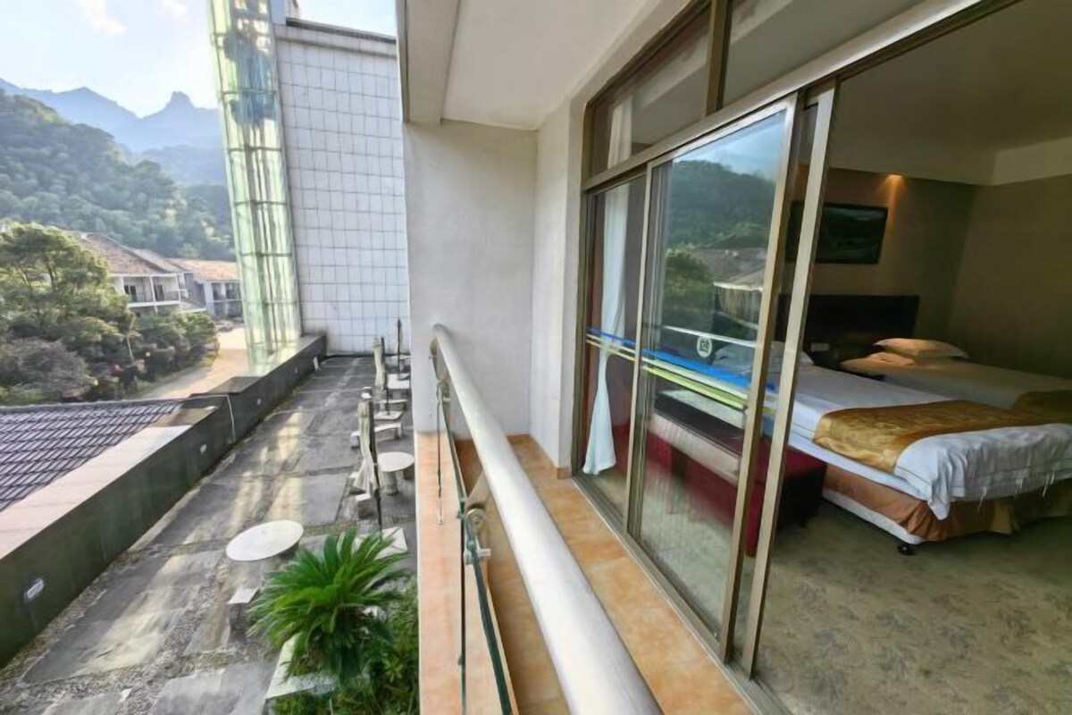 A balcony with a bed, a view of the mountains, and a glass door leading to a room.