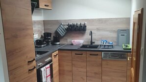 A modern kitchen with wooden cabinets, a black countertop, and a built-in dishwasher.