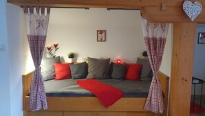 A cozy room with a wooden bed frame, plaid curtains, and a red blanket.
