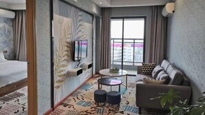 A modern hotel room with a bed, a sofa, a small table, and a TV mounted on the wall. - Foshan Leshui Mansion (Leliu Port West Road Branch) (Foshan)