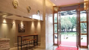 A modern lobby with a marble floor, a reception desk, and a glass door leading outside. - Foshan Leshui Mansion (Leliu Port West Road Branch) (Foshan)