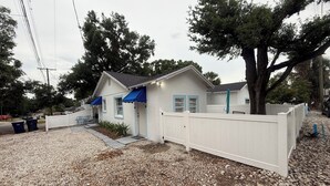A single-story house with a white exterior, blue awnings, and a white picket fence. - Cute Paradise 2 (Tampa)