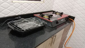 A kitchen with a gas stove, a grill, and a gas cylinder. - Stunning 2-Bed Apartment in Namugongo Town Kampala (Namugongo Town)
