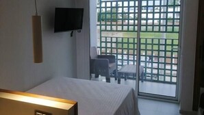 A hotel room with a bed, a TV mounted on the wall, and a balcony with a view of the outdoors. - Charming and Luminous Studio in Lake 1, Tunis (Tunis)