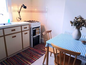 Una cocina compacta con estufa a gas, horno y una pequeña mesa de comedor con sillas.