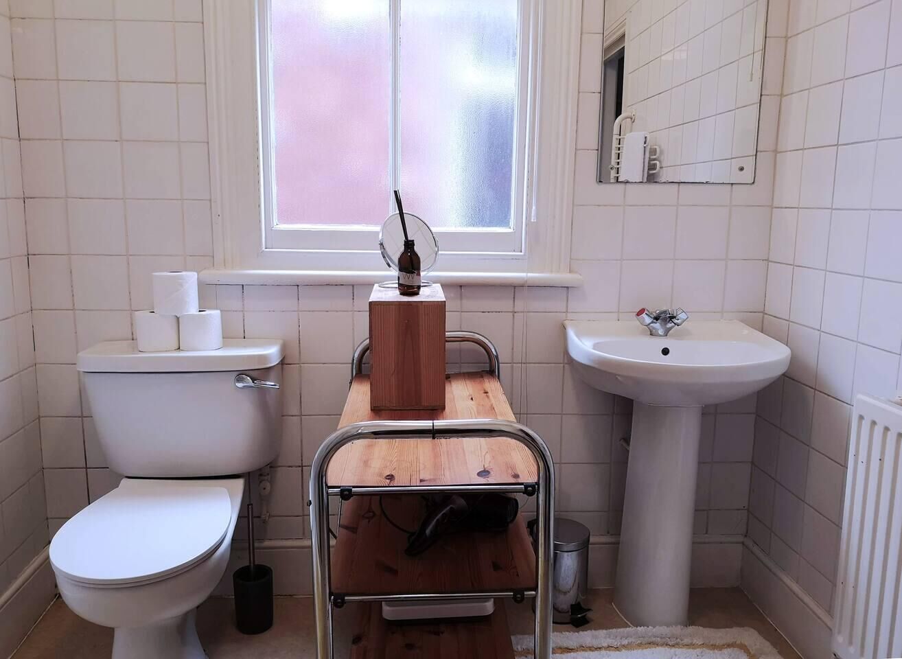 A small bathroom with a toilet, a sink, and a window.