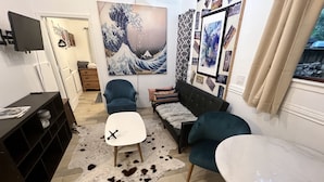 Ein modernes Wohnzimmer mit einer Couch, zwei Sesseln, einem Couchtisch und einem an der Wand befestigten Fernseher.