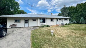 Une maison de plain-pied avec un toit en métal, un porche à l’avant et une allée.