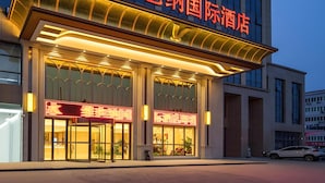 L'entrée d'un hôtel, avec une enseigne bien visible et des fenêtres illuminées.
