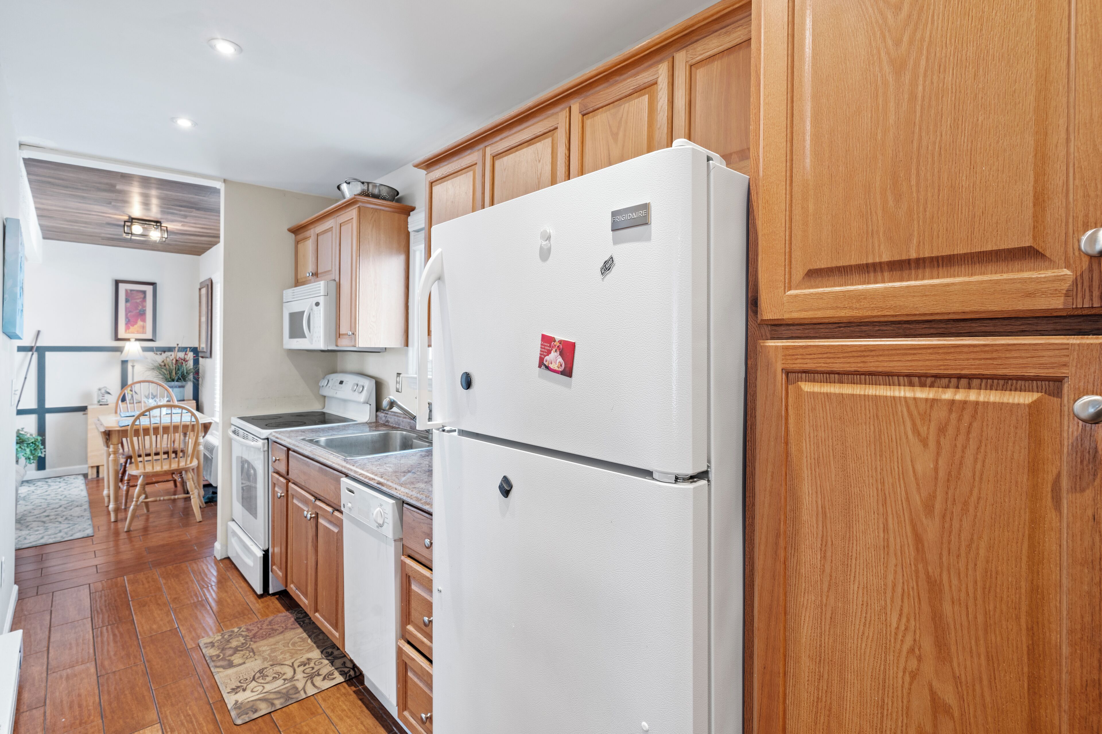 A modern kitchen with wooden cabinets, a white refrigerator, a microwave, and a dishwasher.