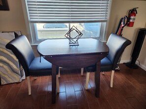 A dining area with a dark wooden table, two blue upholstered chairs, and a decorative metal piece on the table.