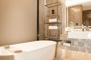 A modern bathroom with a freestanding bathtub, a marble vanity, and a metal shelving unit with towels. - Shunda Shuihui Hotel (Kedong)
