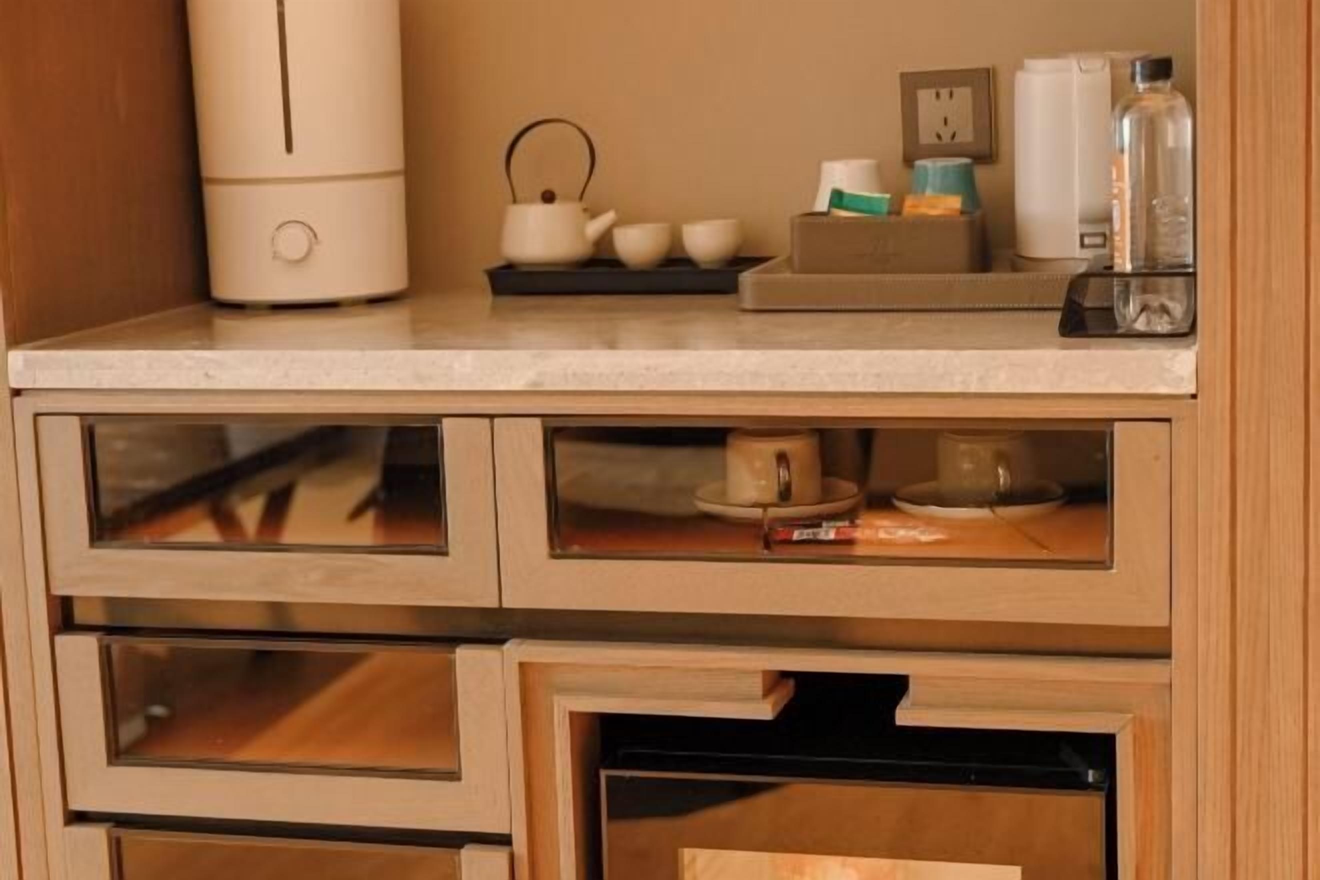 Een keuken met een ingebouwde koffiezetapparaat, theeset en een waterdispenser.