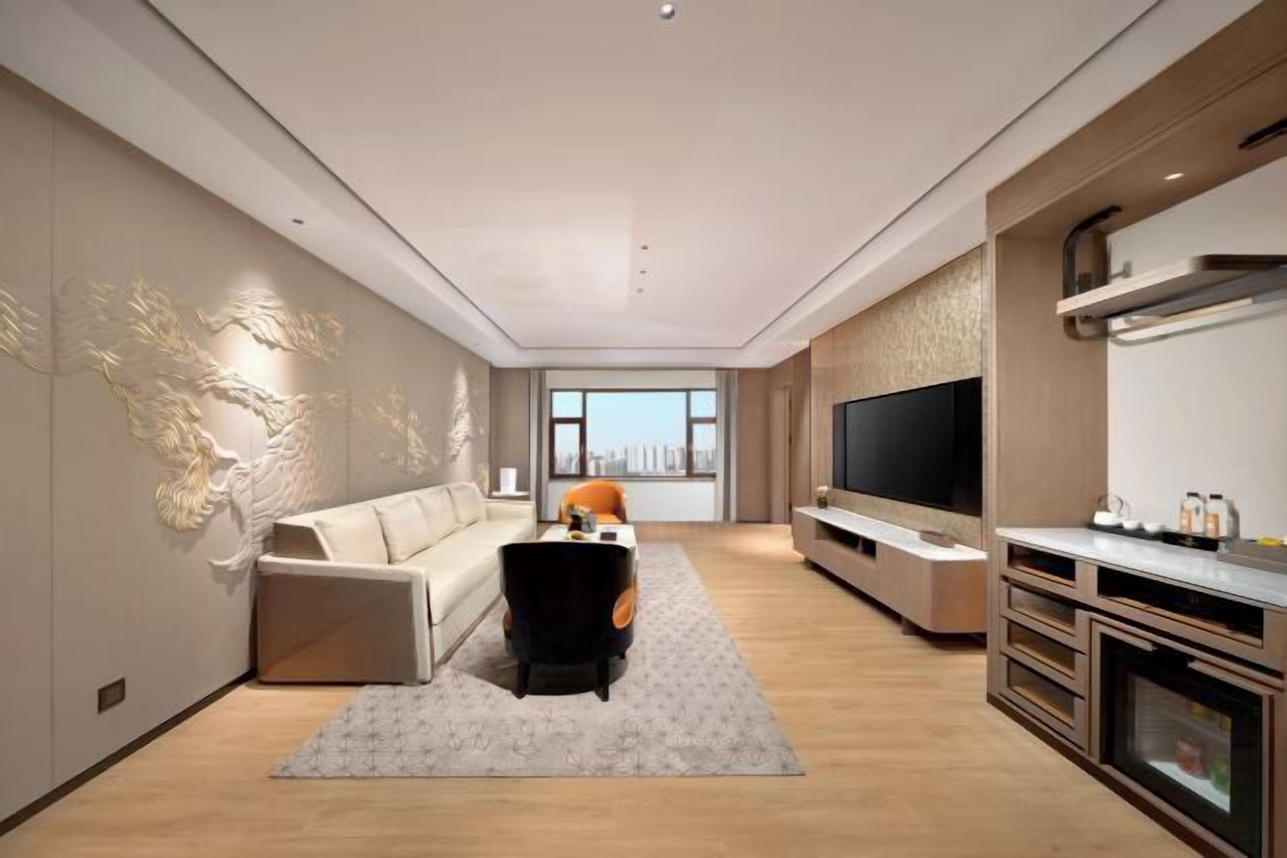 Een moderne woonkamer met een bank, salontafel, televisie en open haard.