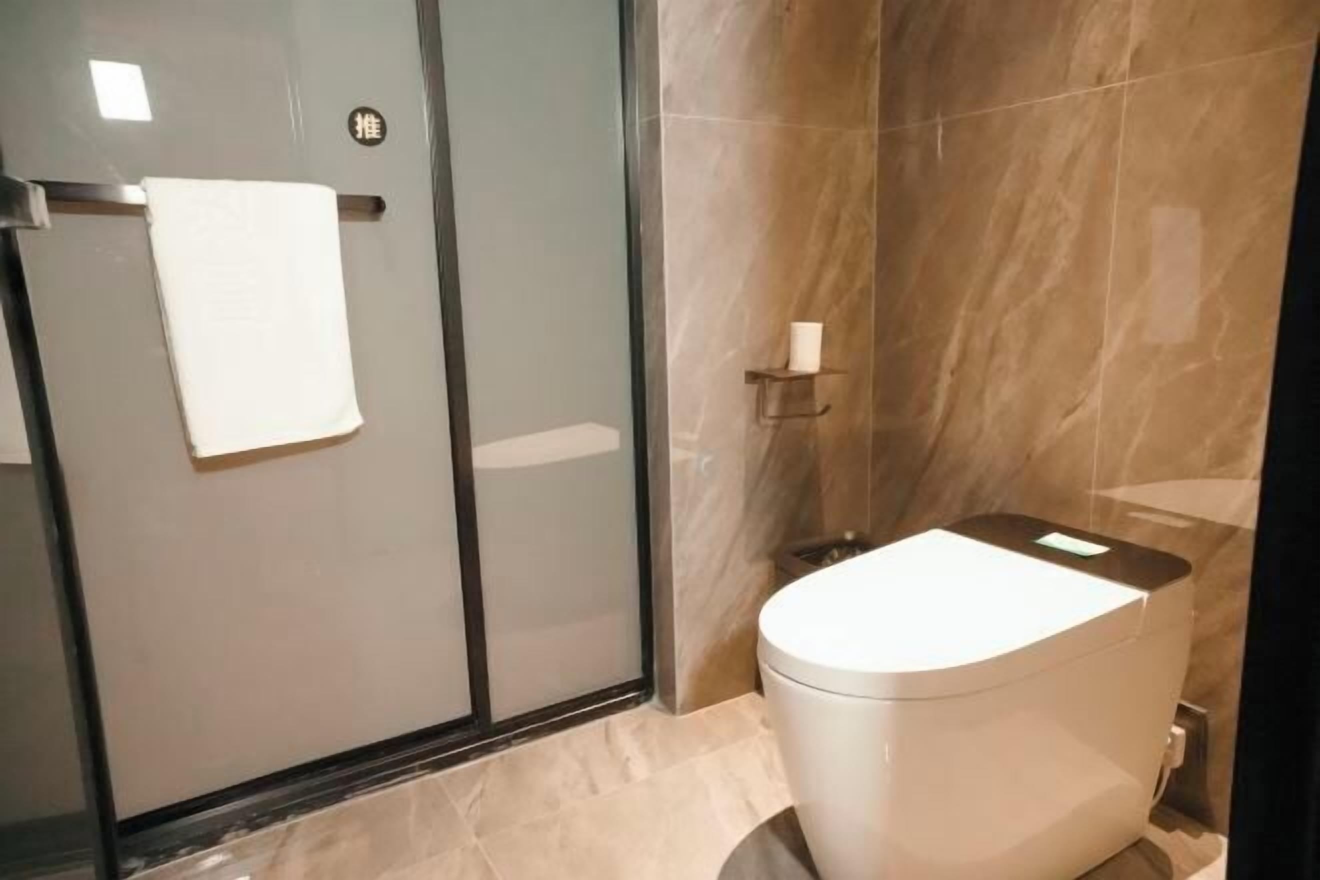 A modern bathroom with a glass shower enclosure, a white toilet, and a marble-tiled wall.