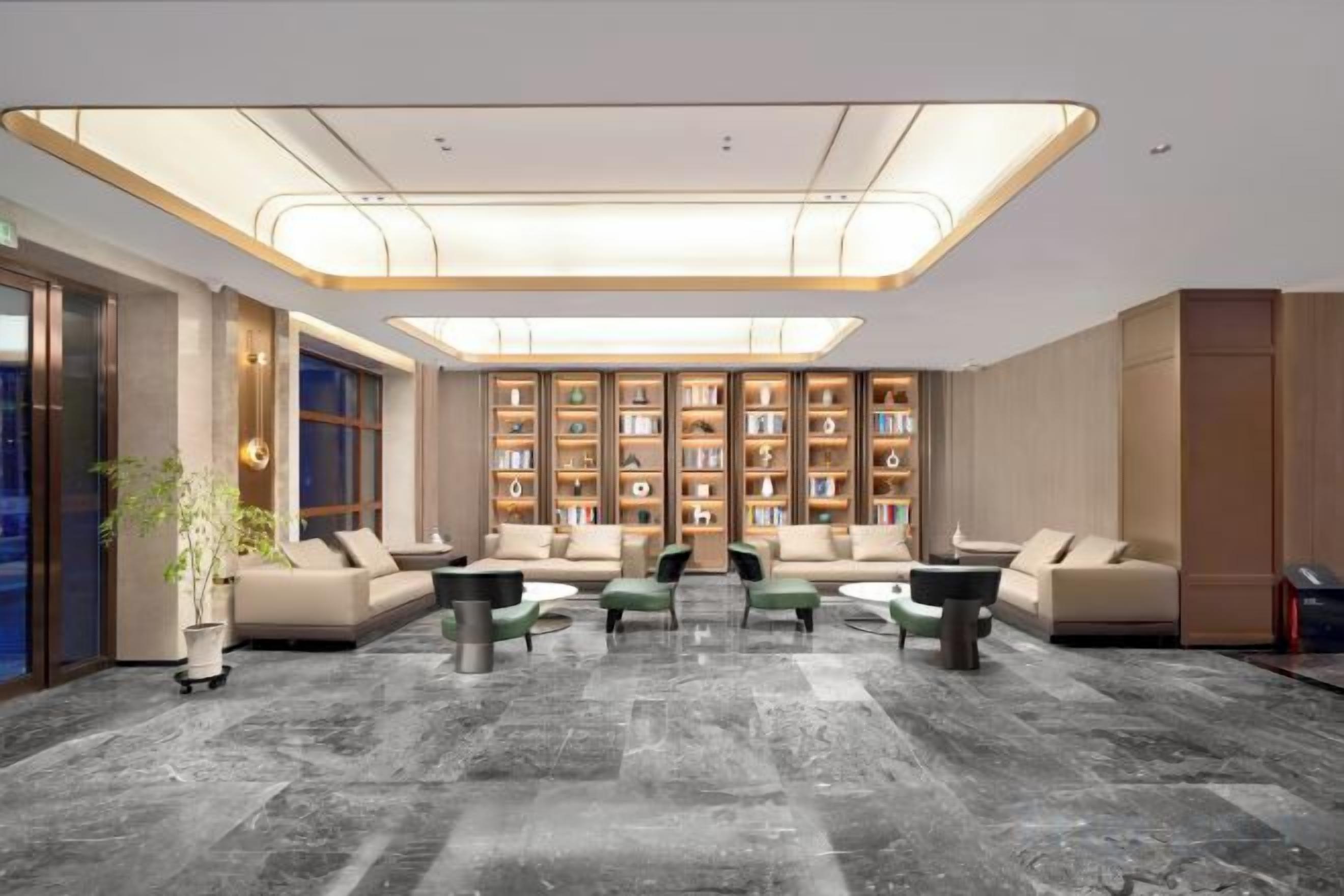A modern lobby with a central seating area, a large bookshelf, and a marble floor.