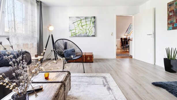 Un salon moderne avec un canapé, un fauteuil, une table basse, une lampe et un tableau au mur.