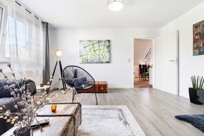 Ein modernes Wohnzimmer mit einer Couch, einem Sessel, einem Couchtisch, einer Lampe und einem Gemälde an der Wand.