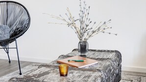 Un banc en bois rustique, sur lequel sont posés un vase rempli de branches séchées, un carnet et un stylo.