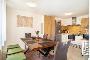Une cuisine moderne avec un coin repas, des meubles en bois et un grand réfrigérateur.