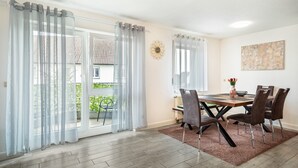 A dining area with a table, chairs, and a view through a glass door. - Apartment 'Tulips' with Shared Garden, Balcony and Wi-Fi (Meckenbeuren)