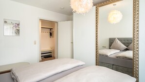 A bedroom with a large mirror, a fluffy light fixture, and a bed with pillows. - Apartment 'Tulips' with Shared Garden, Balcony and Wi-Fi (Meckenbeuren)