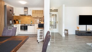 A modern kitchen with a built-in oven, a microwave, and a coffee machine. There is a dining area with a table and chairs. - Apartment 'Tulips' with Shared Garden, Balcony and Wi-Fi (Meckenbeuren)