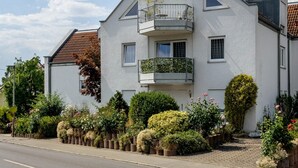 A two-story building with a balcony, a garage, and a well-maintained garden. - Apartment 'Tulips' with Shared Garden, Balcony and Wi-Fi (Meckenbeuren)