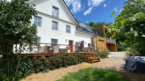 A two-story building with a white exterior, a balcony with wicker furniture, and a red door. - Apartment 'Gästehaus Wüpping 2' with Shared Terrace, Shared Garden and Wi-Fi (Salem)
