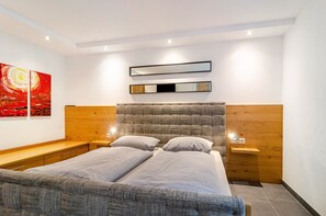 A modern bedroom with a bed, bedside tables, a headboard, and artwork on the wall.