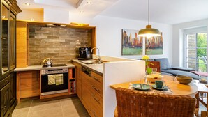 A modern kitchen with a built-in oven, a coffee maker, and a dining area with a wicker table and chairs. - Apartment 'Gästehaus Wüpping 2' with Shared Terrace, Shared Garden and Wi-Fi (Salem)