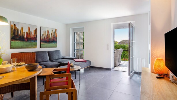 A modern living room with a sofa, dining table, and artwork. - Apartment 'Gästehaus Wüpping 2' with Shared Terrace, Shared Garden and Wi-Fi (Salem)